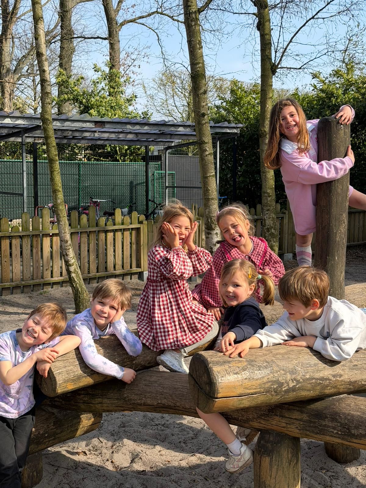Kleuters in hun geruite schoolschort spelen samen buiten